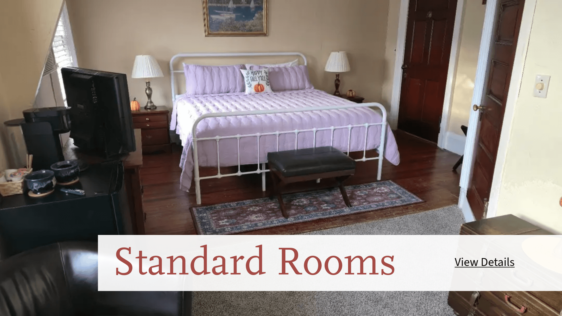 A cozy standard room featuring a double bed, bedside tables, and hardwood floors.