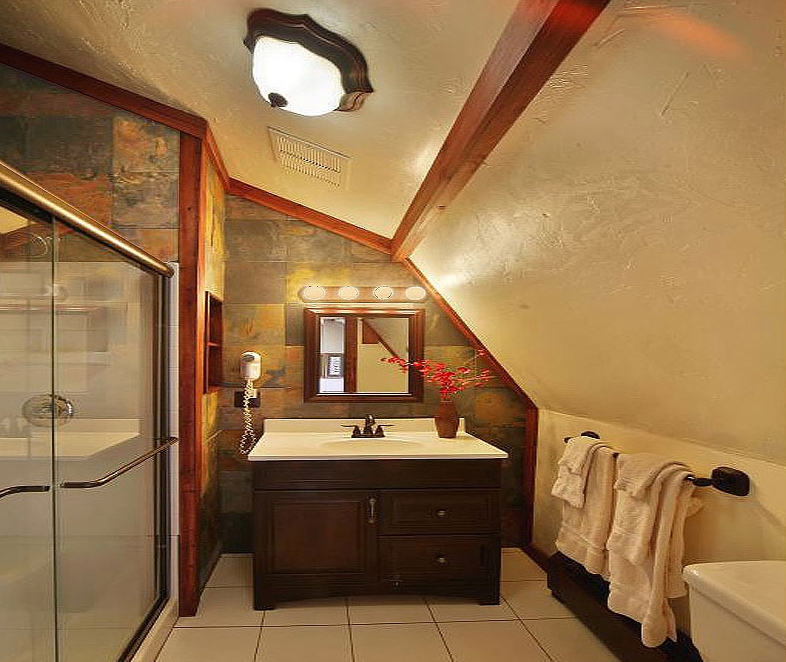 A rustic bathroom featuring a glass shower, dark wood vanity, and walls partially covered in slate tile.