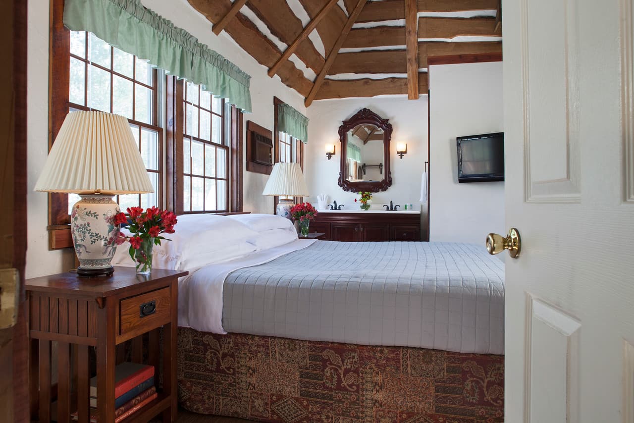 Cozy bedroom featuring a bed, wooden furniture, and large windows with ambient lighting.