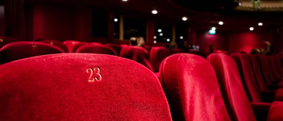 A close-up of a plush red theater seat with the number 23 embroidered.