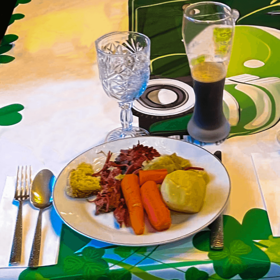 A plate with carrots, lettuce, cabbage, and a roll, accompanied by a glass of water and a dark beverage on a green tablecloth.
