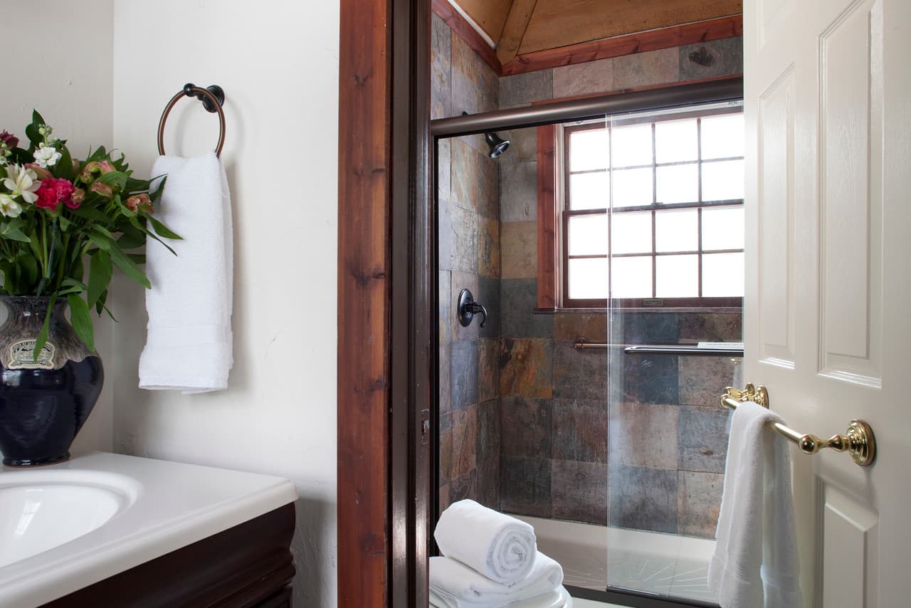 A modern bathroom featuring a glass shower, a vanity with a sink, and decorative flowers.