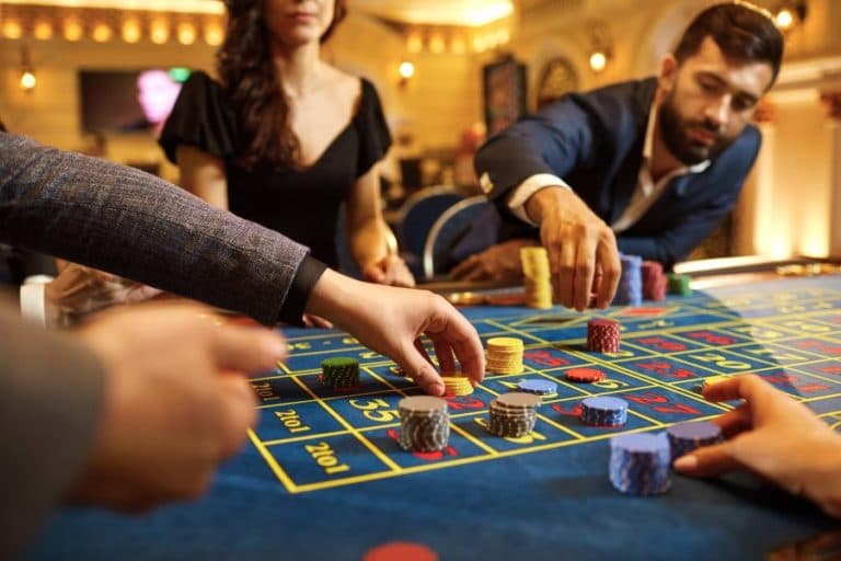 Players placing chips on a roulette table in a casino.