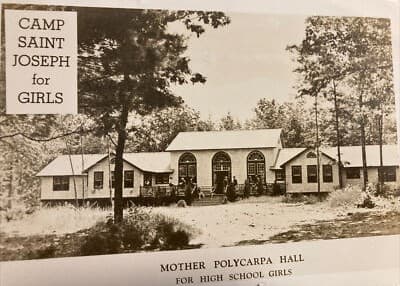 A historical photograph of Mother Polycarpa Hall at Camp Saint Joseph for Girls, surrounded by trees.