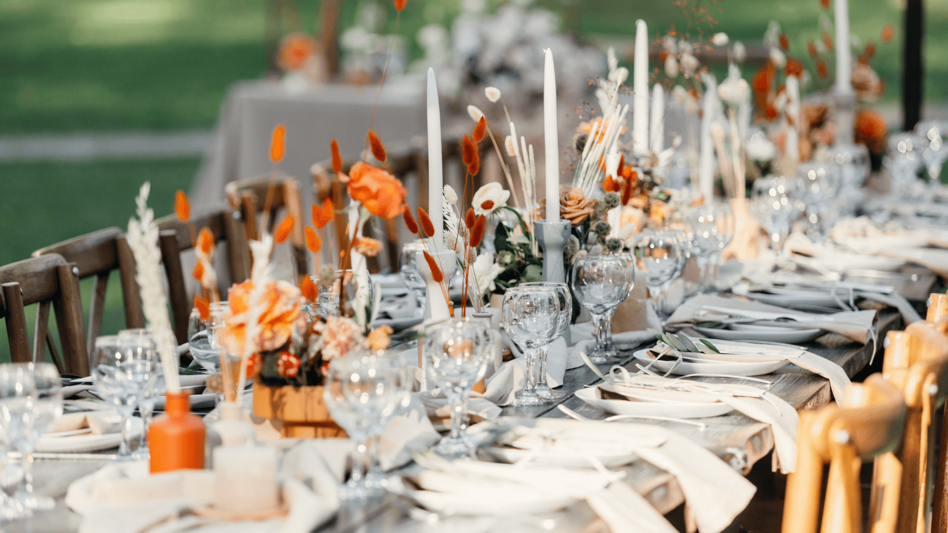 A beautifully arranged outdoor dining table featuring floral centerpieces, glassware, and elegant place settings.