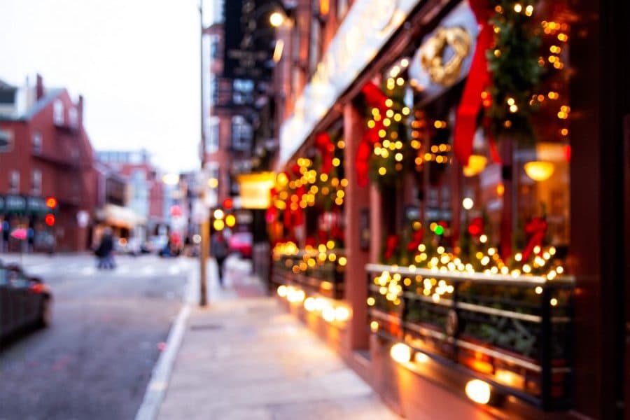 A blurred street scene decorated with festive lights and wreaths.