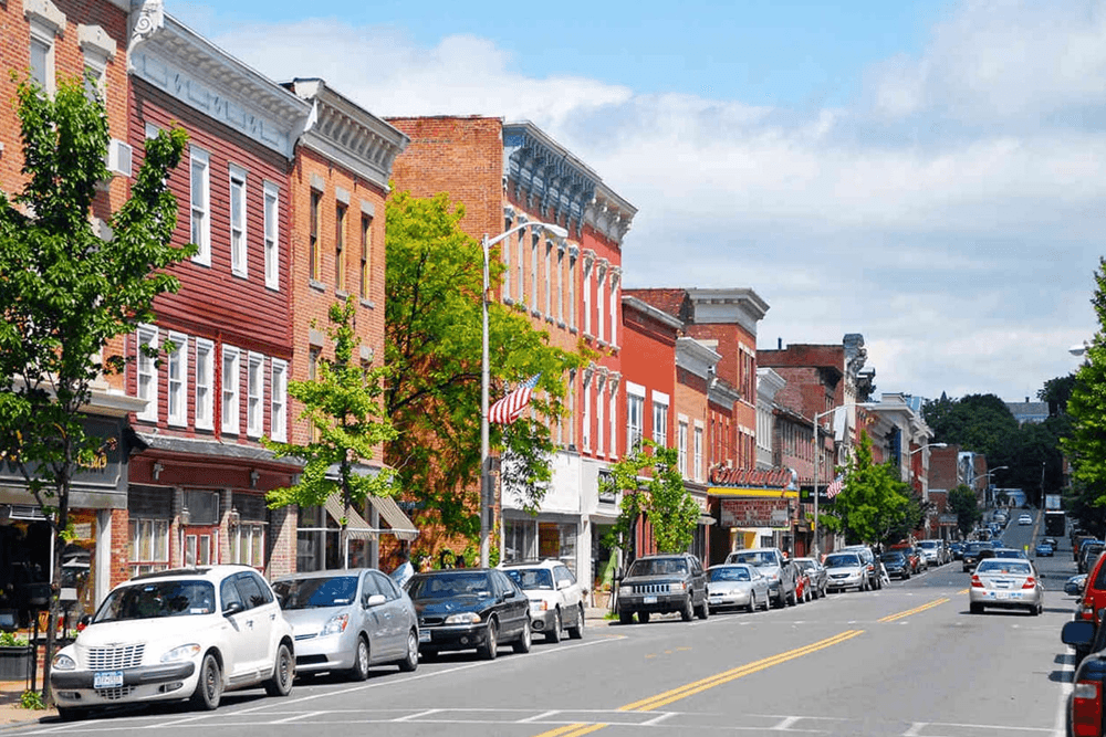 A quaint street lined with colorful historic buildings and parked cars under a blue sky.