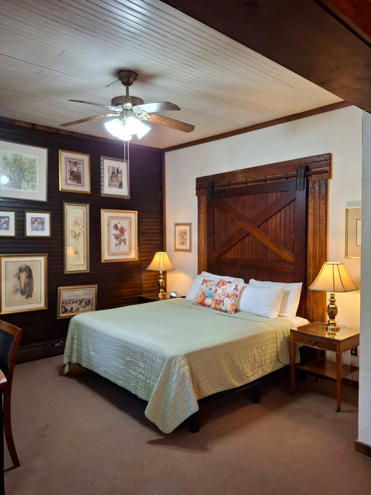 Cozy bedroom with a queen bed, wooden accents, decorative artwork, and warm lighting.