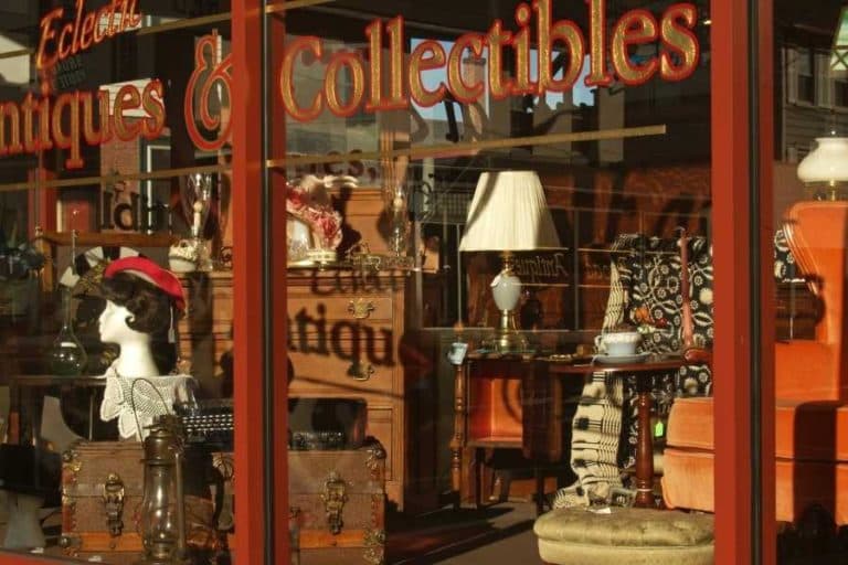 A storefront display featuring various antiques and collectibles, including lamps and decorative items.