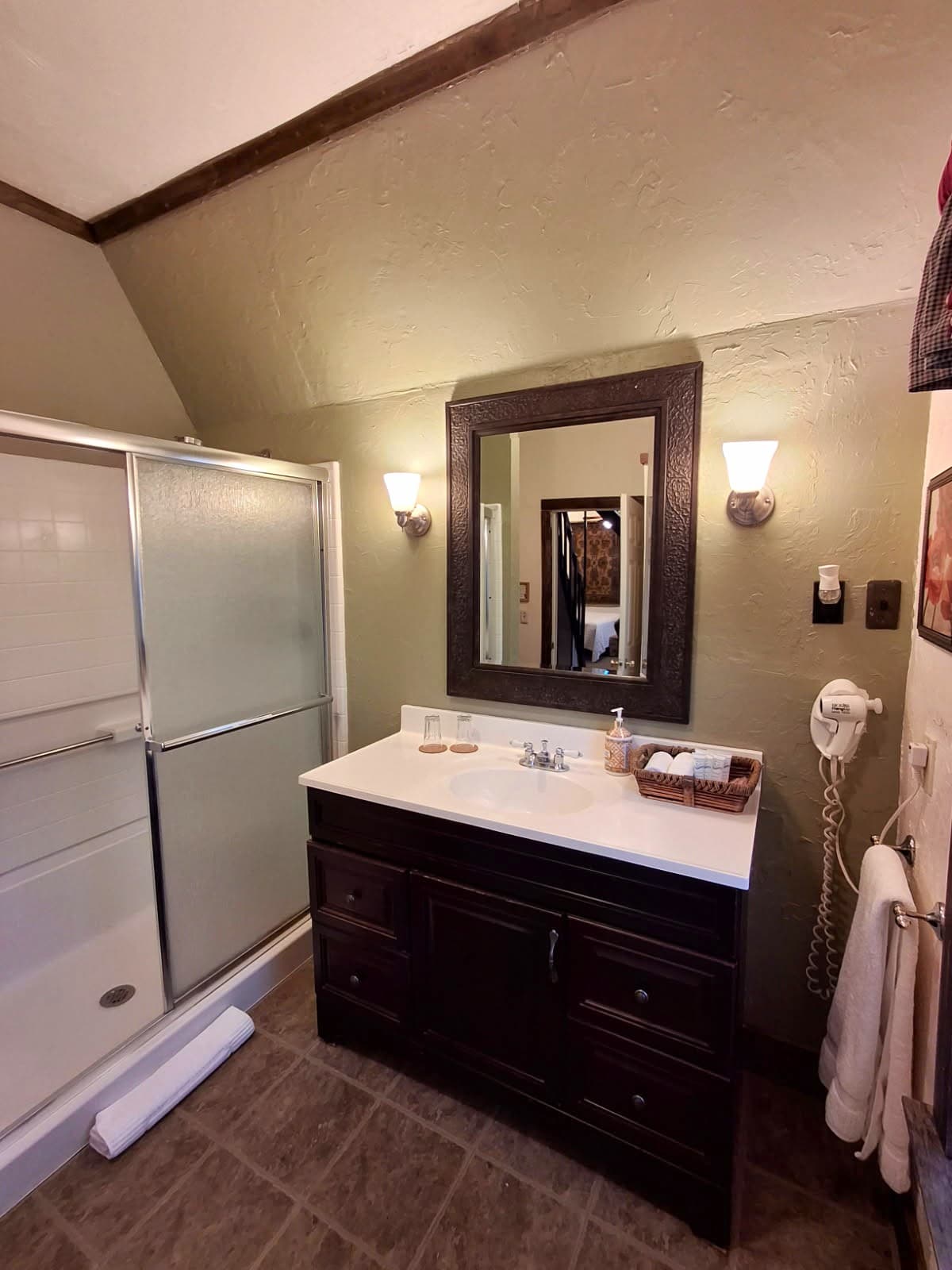 A cozy bathroom featuring a dark wood vanity, a shower stall, and soft lighting.