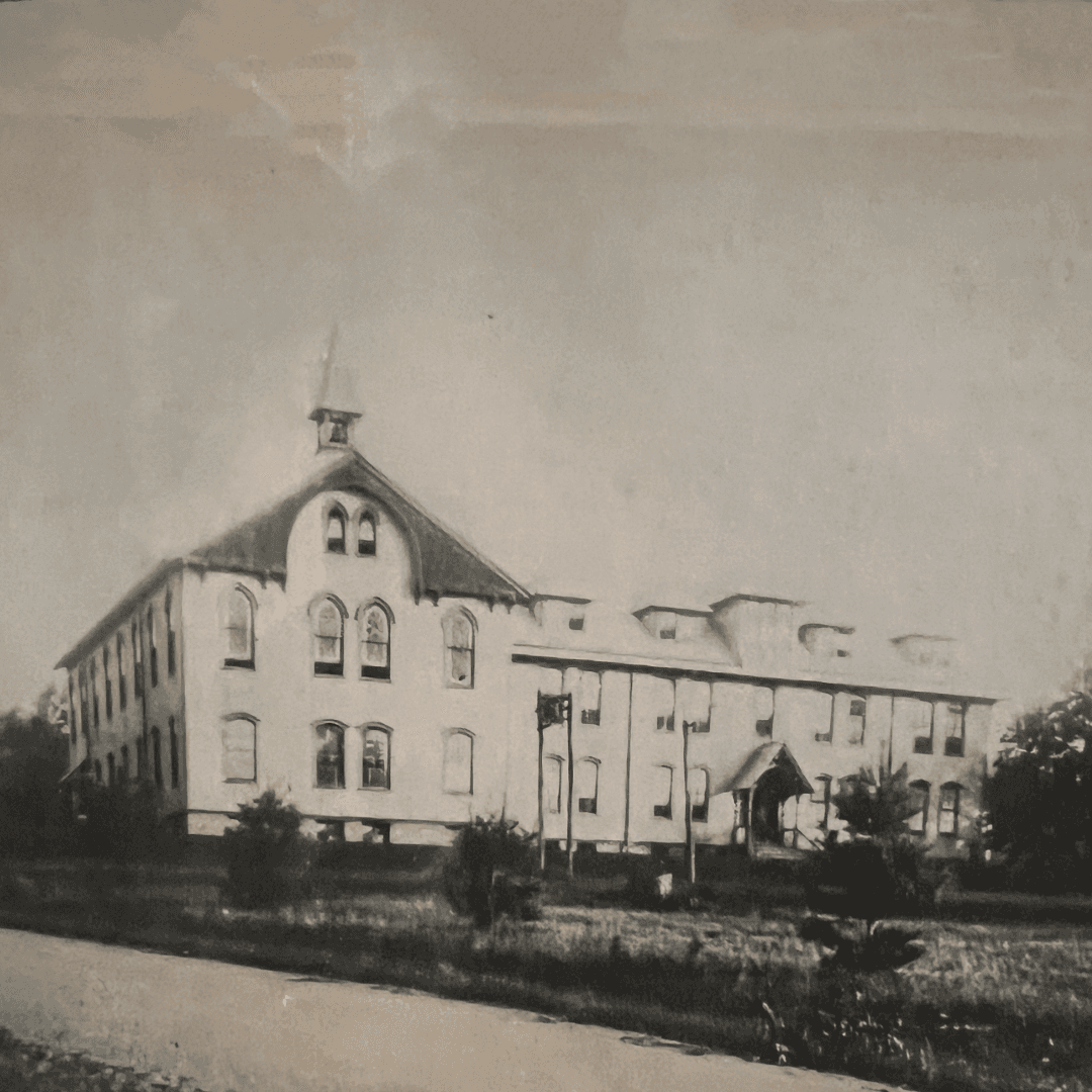 Historic building on Lake Joseph with large windows and a steeple, surrounded by grass.