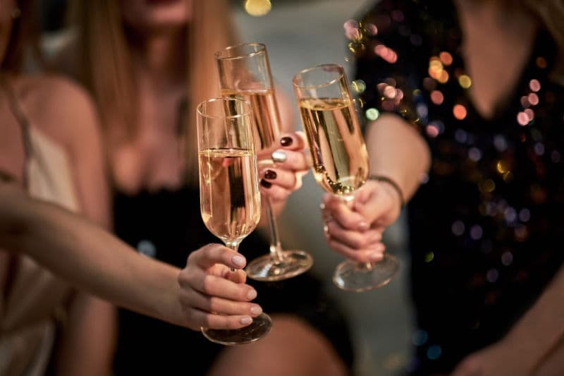 A close-up of several hands toasting with champagne glasses.