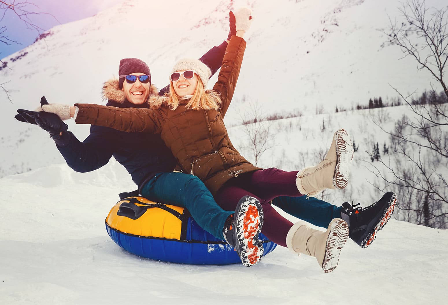 Couple in winter going downhill on a tube